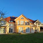 Haus mit Terrasse, Balkon und Garten unter blauem Himmel