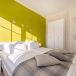 Schlafzimmer mit grünem Wandpaneel, weißem Bett und Kleiderschrank.