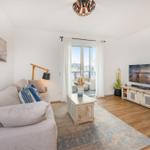 Wohnzimmer mit Sofa, Fernseher und Balkonansicht.
