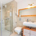 Badezimmer mit Dusche, Waschbecken und Toilette.