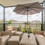Terrasse mit Sitzgruppe, Sonnenschutz und Tisch mit Weinflasche.