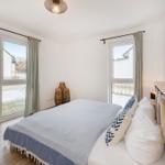Schlafzimmer mit Bett, Fenstern und Holzboden.