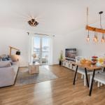 Wohn- und Essbereich mit Sofa, Esstisch und Balkontür.