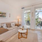 Wohnzimmer mit Sofa, Tischen und Balkonzugang.