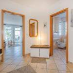 Hausflur mit Blick in Wohnzimmer und Bad, Wandbild Segelboote, Spiegel und Holzrahmen