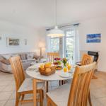 Esszimmer mit Tisch, Stühlen und Frühstück. Wohnbereich mit Sofa und Fenster.