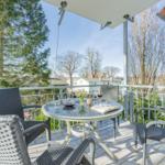 Terrasse mit Tisch und Stühlen, Blick auf Bäume und Häuser.