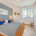 Schlafzimmer mit Holzbett, Fenster und Kleiderschrank.