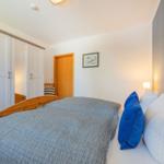 Schlafzimmer mit Bett, Kleiderschrank und Wandspiegel.
