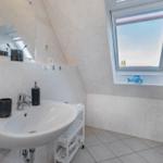 Badezimmer mit Waschbecken, Spiegel und Dachfenster.