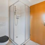 Badezimmer mit Dusche, Toilette und Heizung.