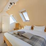 Schlafzimmer mit Dachschrägen, Dachfenster, Bett und Schrank.