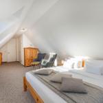 Schlafzimmer mit Dachschrägen, Bett, Fernseher und Sitzgelegenheit.