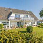 Einfamilienhaus mit Balkon, Garten und Pflanzen. Modernes Design mit großen Fenstern.
