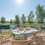Terrasse mit Tisch und Stühlen, Blick auf grüne Landschaft und Bäume.