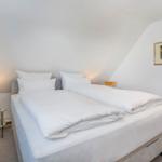Schlafzimmer mit Doppelbett, Nachttisch und Wandbild.