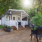 Haus mit Holzterrasse, weißen Geländern und Gartenmöbeln.