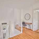 Helle Etage mit Holzboden, weißer Brüstung und Schreibtisch an der Wand.