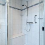 Dusche mit Glaswand, Sitzbank und Duschbrause