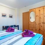 Schlafzimmer mit Bett, Holzschrank und Wandbildern.