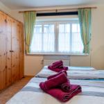 Zimmer mit zwei Betten, Holzschrank und Fenster mit Vorhängen.