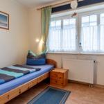 Ein Schlafzimmer mit Bett, Nachttisch und Fenster. Auf dem Bett liegen Handtücher.