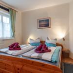 Schlafzimmer mit Holzbett, Fenster und Bildern an der Wand.