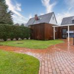 Hinterhof mit Grill, Terrasse und Garten. Holzhaus und Zwerchhaus im Hintergrund.