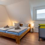 Doppelbett mit blauen Matratzen, Kinderbett und zwei Fenster