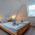 Schlafzimmer mit Dachschräge, Holzbett, Fenster und Sessel.
