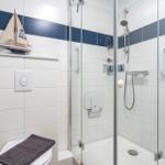Badezimmer mit Dusche, Toilette und Segelboot-Dekoration.