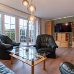 Wohnzimmer mit zwei Ledersesseln, Glas-Tisch und Fernseher an Wand.