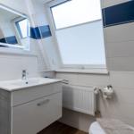Badezimmer mit Waschbecken, Spiegel und Dachfenster.