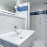 Badezimmer mit Dusche, Waschbecken und Spiegel.