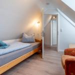 Schlafzimmer mit Dachschrägen, Bett und Sessel