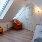 Dachgeschosszimmer mit Bett, Sessel und Dachfenster.