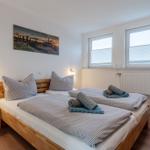 Schlafzimmer mit Doppelbett, Wandbild, zwei Fenstern und TV.