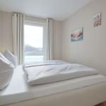 Schlafzimmer mit Bett, Fenster und Wandbildern.