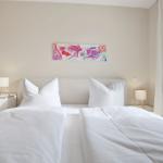 Schlafzimmer mit Doppelbett, Nachttischen und Fenster. Wandbild über dem Bett.