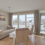 Wohnzimmer mit Sofa, Sessel und Blick auf Balkon