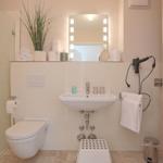 Badezimmer mit Dusche, Waschbecken, Toilette und Spiegelschrank.