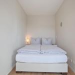 Schlafzimmer mit Doppelbett, Nachttisch und Lampe.