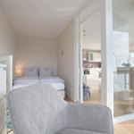 Schlafzimmer mit Bett und Sessel, Blick in Küche und Wohnbereich.