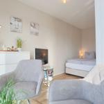 Ein Schlafzimmer mit Bett, zwei Sesseln und Fernseher. Fenster mit Blick nach draußen.