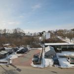Schneebedeckter Parkplatz mit Fahrradverleih und Wohnhäusern im Hintergrund.