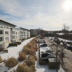 Winterlicher Blick auf Wohngebäude und Parkplatz mit Schnee und Bäumen.
