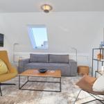 Wohnzimmer mit grauem Sofa, gelber Sessel und Holztisch unter Dachschräge.
