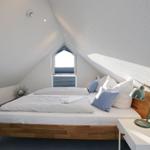 Schlafzimmer mit Dachschrägen, Bett, Nachttisch und Fenster