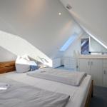 Schlafzimmer mit Dachschräge, Bett, Nachttisch und Schrank.