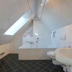 Badezimmer mit Dusche, Badewanne, Waschbecken und Toilette unter Dachschrägen mit Dachfenster.